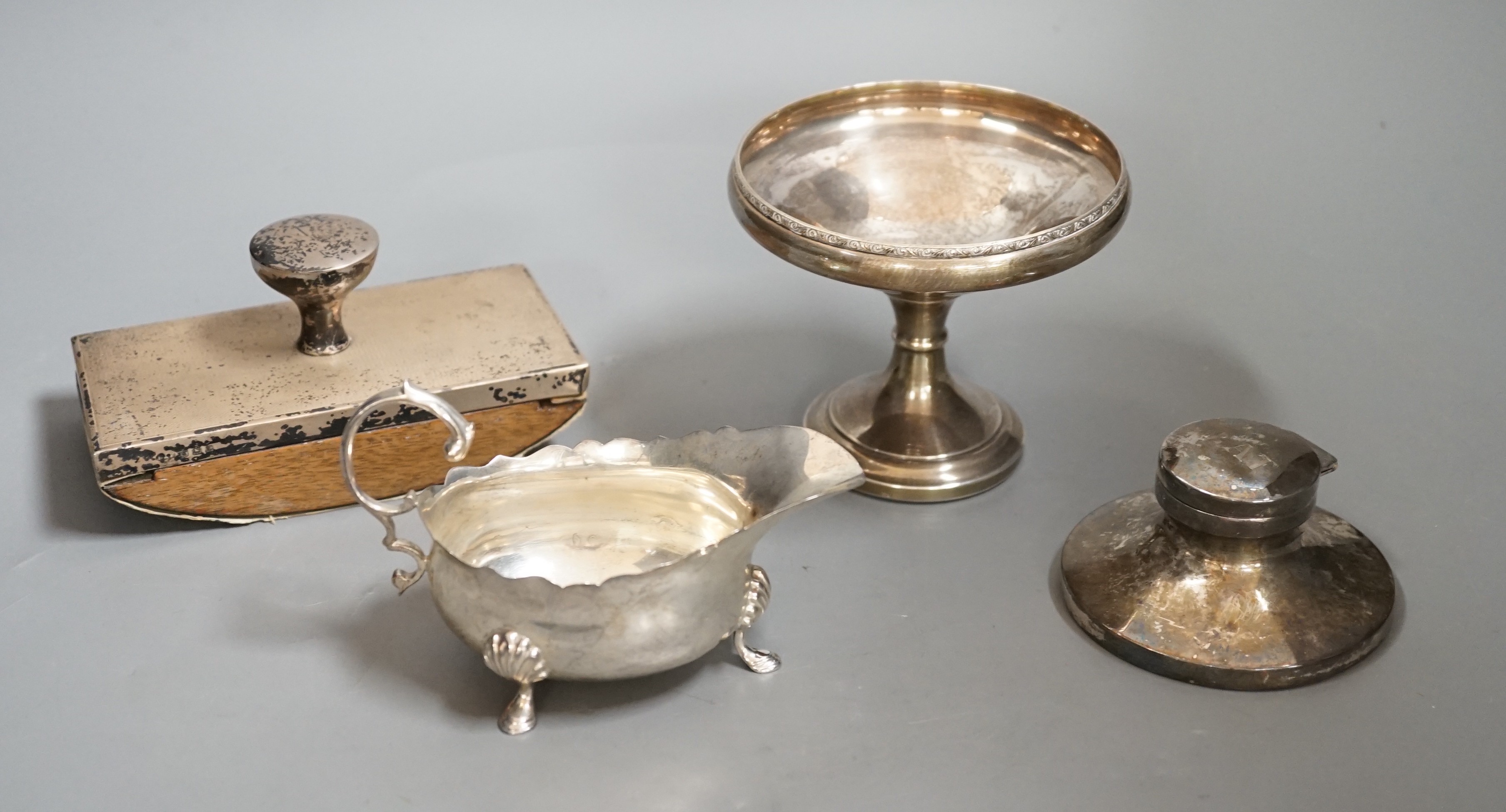 A George VI silver sauceboat, London, 1937, a silver mounted blotter, a silver mounted capstan inkwell and a silver tazze.